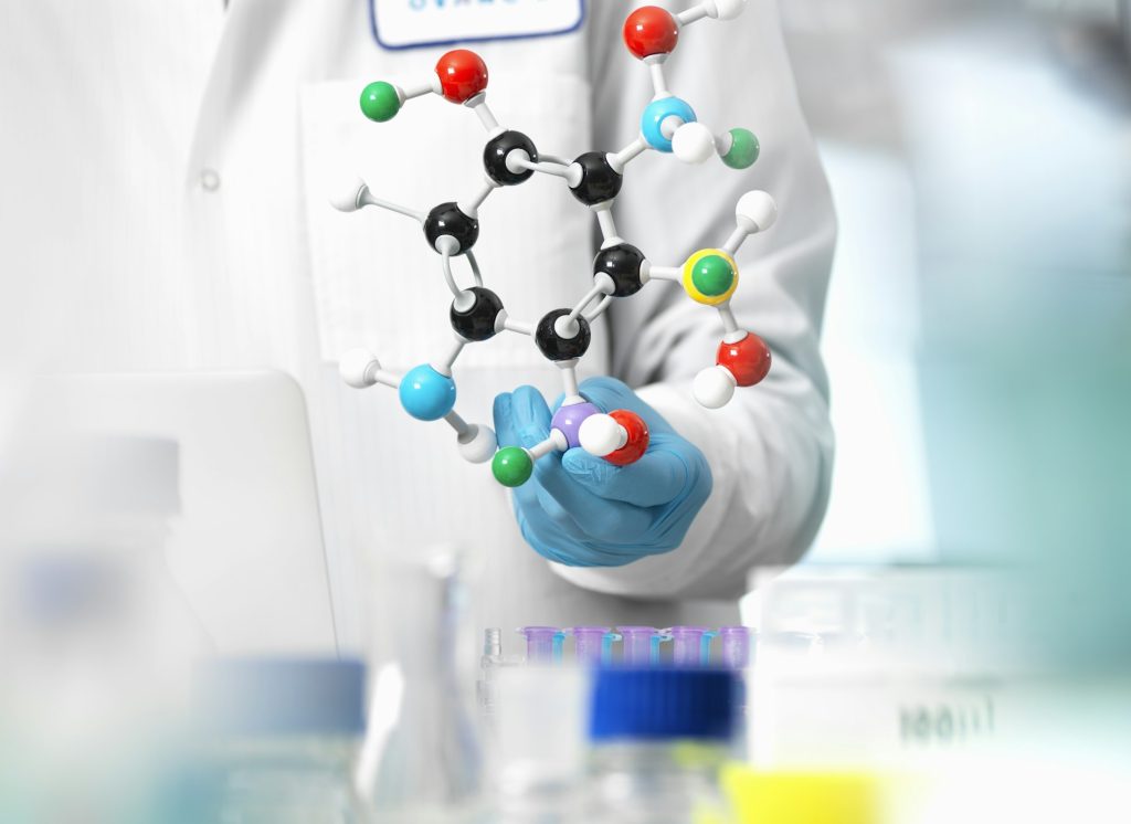 Researcher using a molecular model to understand a chemical formula in a laboratory